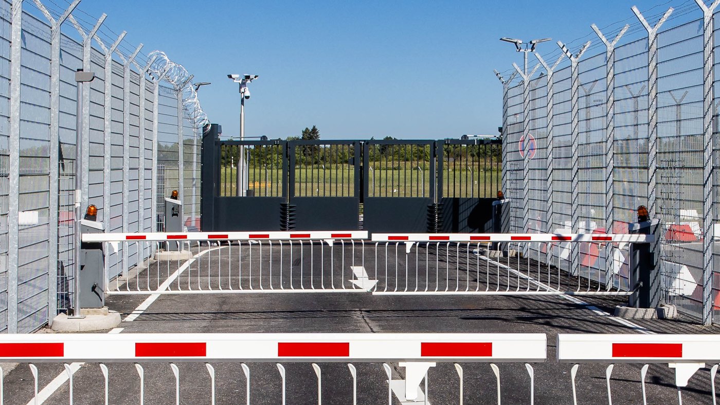 Gesicherte Zufahrt mit Schranken, Zaunanlage und Faltflügeltor